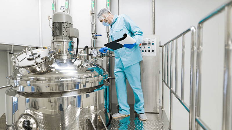 funcionário operando uma máquina de produção de medicamentos