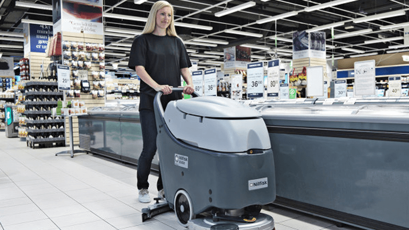 mulher limpando o chão de um supermercado com uma máquina de limpeza